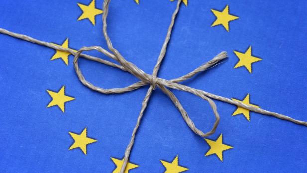 Ein Geschenk, verpackt in blauem Papier mit gelben Sternen und einer Kordel.