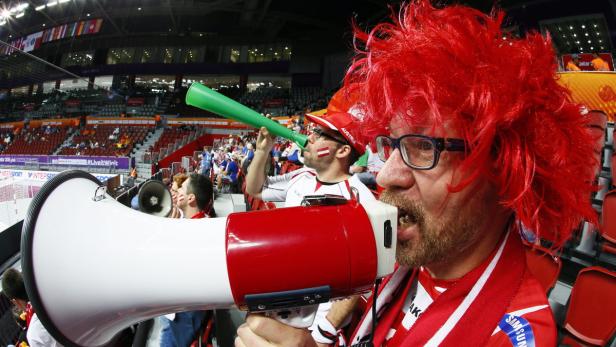 Ein österreichischer Fan mit roter Perücke schreit durch ein Megafon.