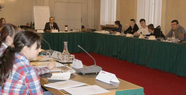 Eine Gruppe von Menschen sitzt an einem langen Tisch während einer Konferenz.