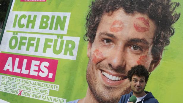 Ein Mann steht vor einem Wahlplakat der Grünen mit dem Slogan „Ich bin Öffi für alles.“.
