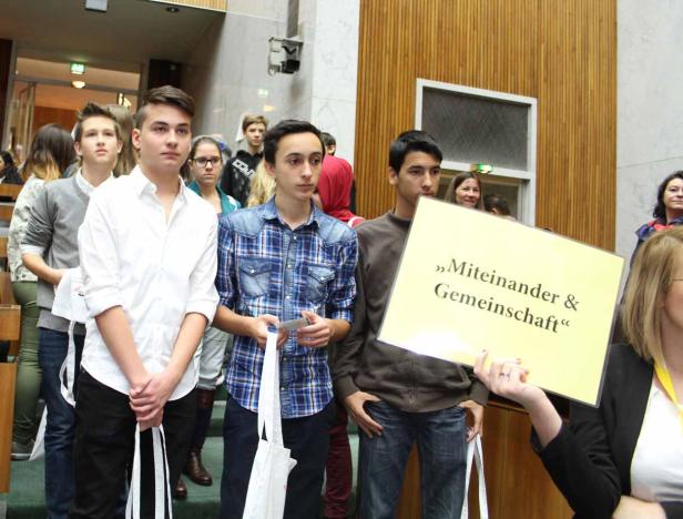 Eine Gruppe junger Menschen hält ein Schild mit der Aufschrift „Miteinander & Gemeinschaft“.