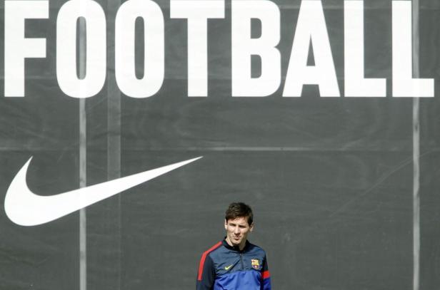 Lionel Messi steht vor einer Wand mit der Aufschrift „Football“ und einem Nike-Logo.