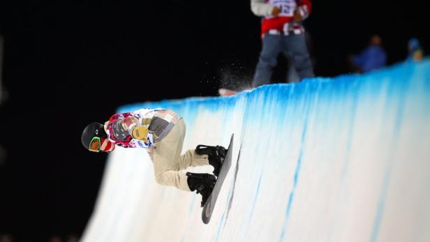 Ein Snowboarder fährt eine Halfpipe hinunter.
