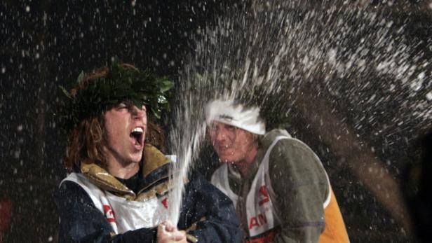 Zwei Männer mit Lorbeerkränzen feiern mit Champagner.