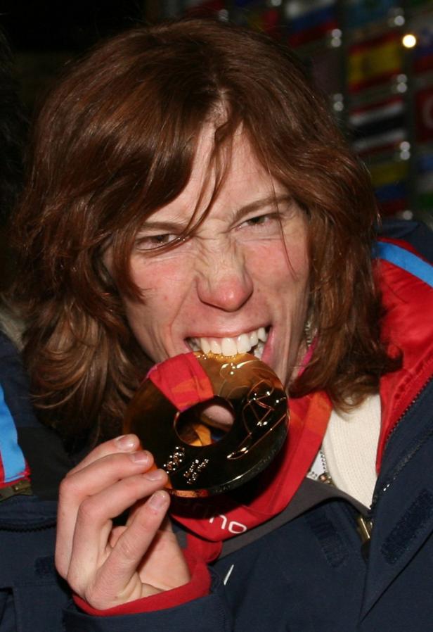 Eine Frau beißt in ihre Goldmedaille.