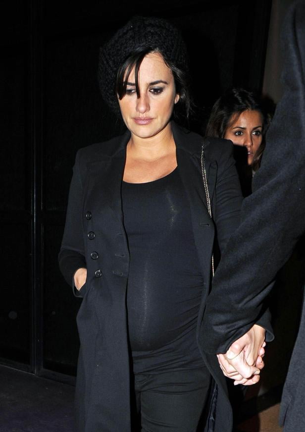 Eine schwangere Frau, vermutlich Penélope Cruz, mit schwarzer Mütze und Mantel, hält Händchen.