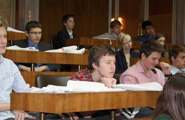 Mehrere Jugendliche sitzen in einem Hörsaal an ihren Tischen.