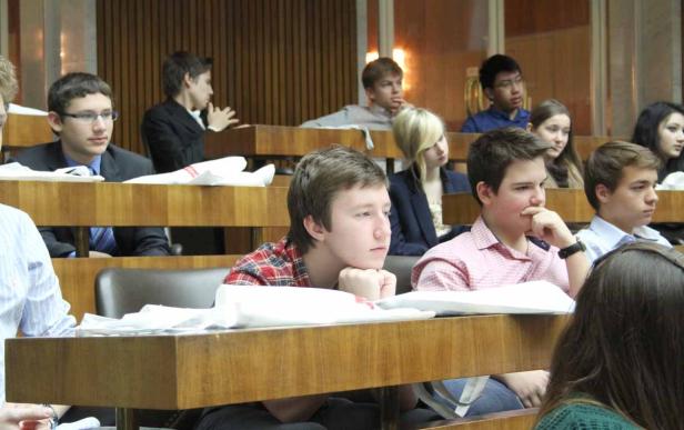 Mehrere Studenten sitzen in einem Hörsaal und hören aufmerksam zu.