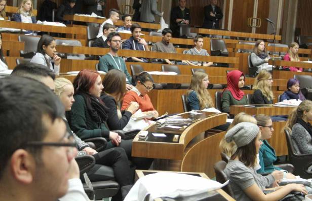 Zahlreiche Menschen sitzen in einem Hörsaal oder Konferenzraum.