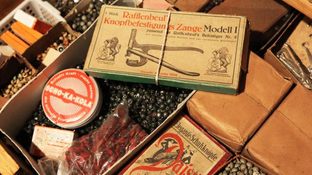 Eine Kiste mit verschiedenen alten Artikeln, darunter eine „Rafflenbeul“-Zange und Schoko-Ka-Kola.