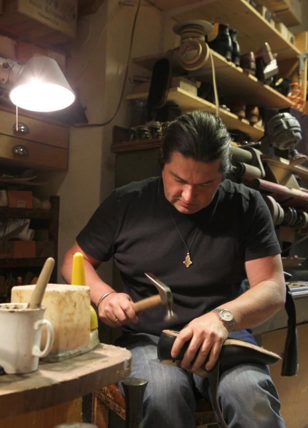 Ein Schuster repariert einen Schuh mit einem Hammer in seiner Werkstatt.