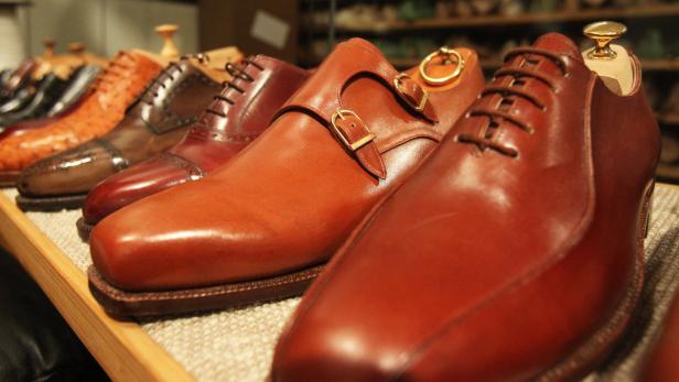 Eine Reihe verschiedener Lederschuhe stehen auf einem Regal.