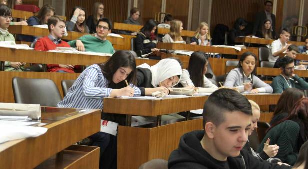 Viele Studenten sitzen in einem Hörsaal und machen sich Notizen.