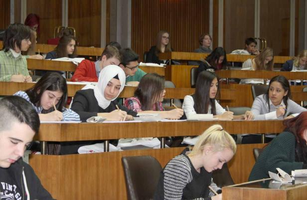 Eine Gruppe Studenten sitzt in einem Hörsaal und schreibt Klausur.
