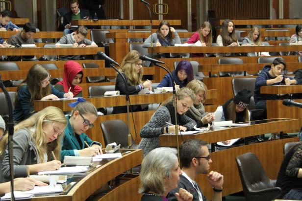 Viele Studenten sitzen in einem Hörsaal und machen sich Notizen.