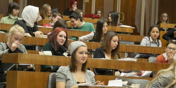 Zahlreiche Studenten sitzen in einem Hörsaal und hören aufmerksam zu.