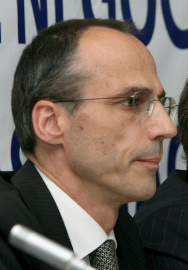 Ein Mann mit Brille und Anzug im Profil.