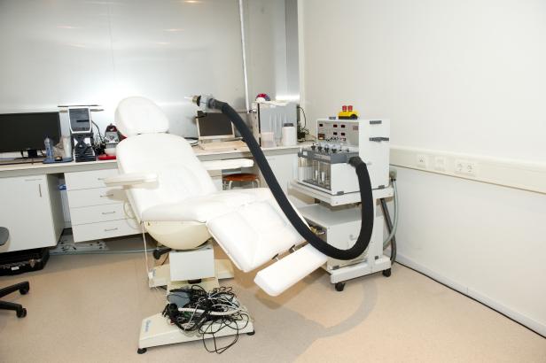 Ein weißer Behandlungsstuhl mit medizinischen Geräten in einem Untersuchungsraum.