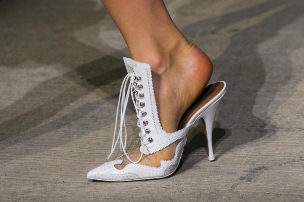 Ein Fuß in einem weißen, hochhackigen Schnürschuh mit transparenten Einsätzen.