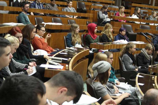 Zahlreiche Studenten sitzen in einem Hörsaal und hören aufmerksam zu.