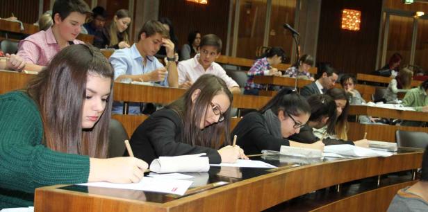 Schüler sitzen in einem Hörsaal und schreiben eine Klausur.