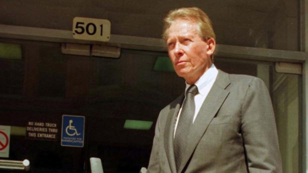 Ein Mann im Anzug steht vor einem Gebäude mit der Nummer 501.