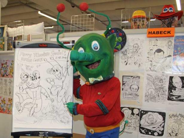 Ein Mann im Kostüm einer Comicfigur präsentiert eine Zeichnung von Perry Rhodan.