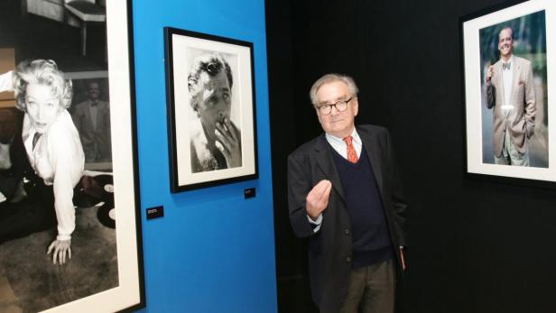 Ein Mann steht in einer Kunstgalerie vor Porträtfotografien.