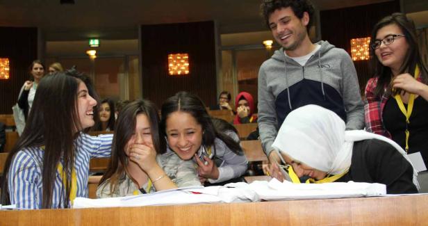 Eine Gruppe junger Leute sitzt in einem Hörsaal und lacht.