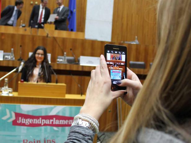 Eine Frau filmt mit ihrem Smartphone eine Rednerin im Jugendparlament.