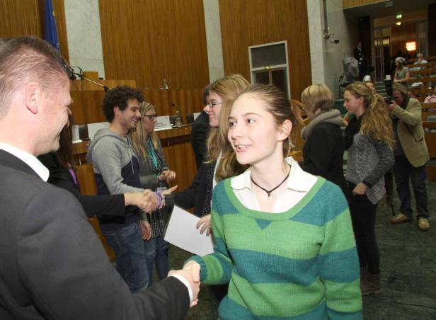 Eine junge Frau schüttelt in einem formellen Rahmen Hände.