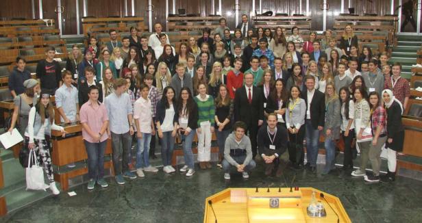 Eine große Gruppe junger Leute posiert in einem Sitzungssaal für ein Foto.