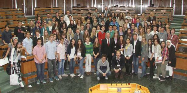 Eine große Gruppe von Menschen steht in einem Sitzungssaal.