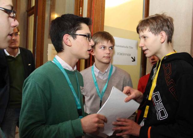 Eine Gruppe Jugendlicher unterhält sich vor einer Tür mit dem Hinweis „Automatische Türe“.