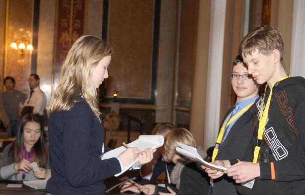 Eine Gruppe junger Leute bei einer Veranstaltung, einige mit Notizblöcken.