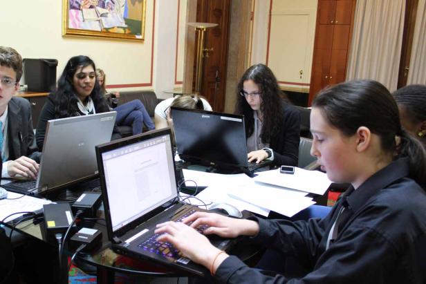 Eine Gruppe von Studenten arbeitet an Laptops in einem Raum.