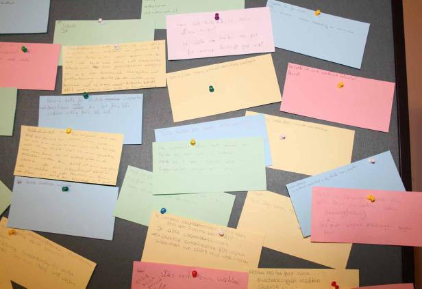 Eine Pinnwand mit vielen bunten Notizen, die mit Reißzwecken befestigt sind.