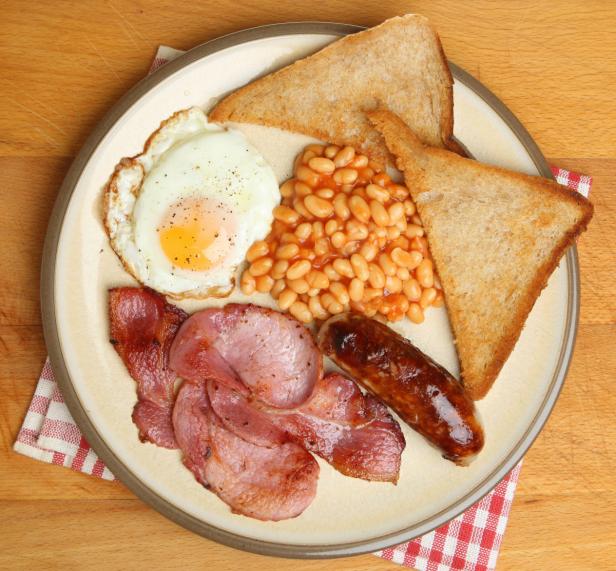 Ein Teller mit einem traditionellen englischen Frühstück mit Ei, Speck, Wurst, Bohnen und Toast.