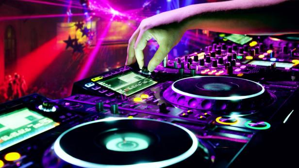 Die Hand eines DJs bedient ein Mischpult in einem Nachtclub.