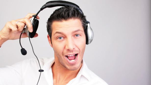 Ein Mann mit offenem Mund hält ein Headset in der Hand.