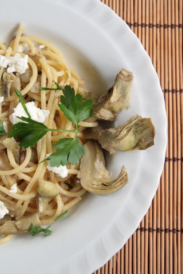 Ein Teller Spaghetti mit Artischocken, Feta und Petersilie.
