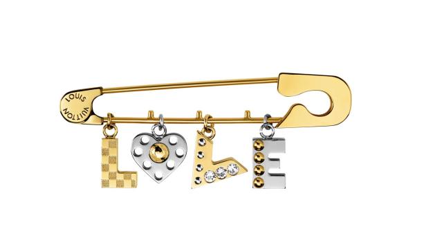 Eine goldene Brosche von Louis Vuitton in Form einer Sicherheitsnadel mit dem Wort „LOVE“ als Anhänger.