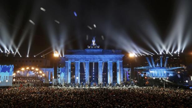 Eine große Menschenmenge versammelt sich vor dem beleuchteten Brandenburger Tor in Berlin.