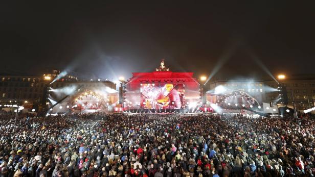 Eine große Menschenmenge versammelt sich vor dem Brandenburger Tor für eine Veranstaltung mit Bühne und Lichtern.
