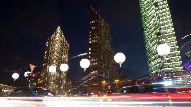 Nachts beleuchtete Gebäude am Potsdamer Platz in Berlin mit Straßenverkehr.