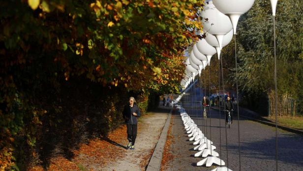 Eine Frau joggt auf einem von Herbstlaub bedeckten Weg, während Radfahrer vorbeifahren.
