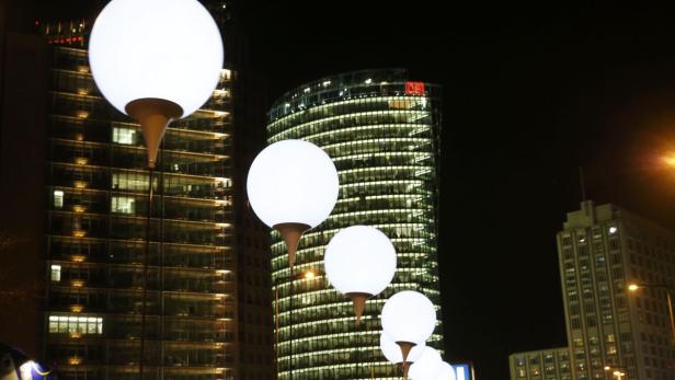 Nachts leuchten kugelförmige Lampen vor der Kulisse von Bürogebäuden in Berlin.