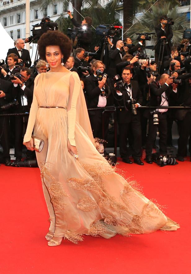 Solange Knowles in einer goldenen Robe auf dem roten Teppich, umringt von Fotografen.