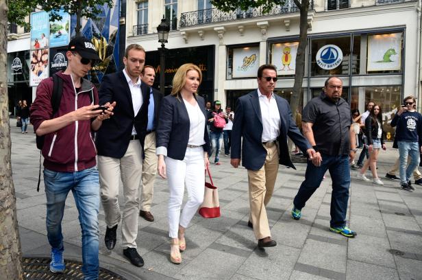 Arnold Schwarzenegger geht mit Begleitern auf den Champs-Élysées in Paris entlang.