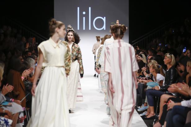 Models präsentieren Mode der Marke „lila“ auf einem Laufsteg.